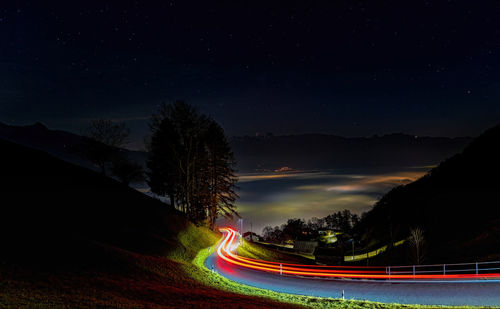 Light trails on road against sky at night