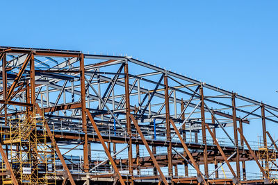 Low angle view of rollercoaster against clear blue sky