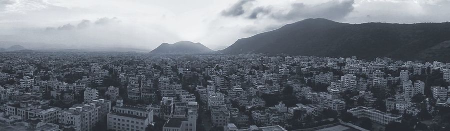 Aerial view of cityscape against cloudy sky