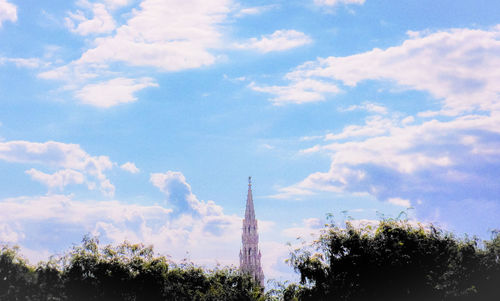 Low angle view of communications tower against cloudy sky