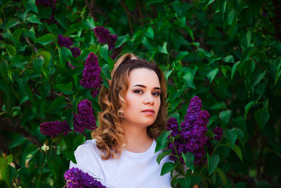 Portrait of beautiful young woman against purple flowering plants