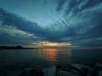 Scenic view of sea against dramatic sky during sunset