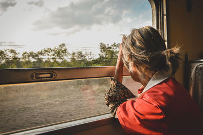 Senior woman looking through train window against sky