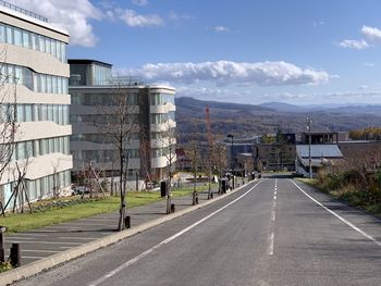 Road amidst buildings in city against sky