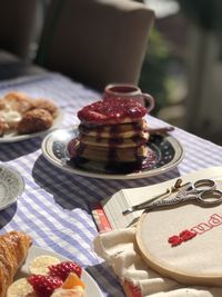 Sunny breakfast table with pancakes and jelly and a book with an embroidery hoop. 
