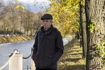 Portrait of man standing by tree trunk