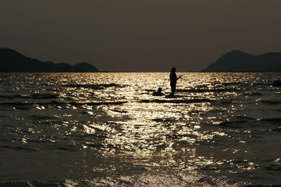 Silhouette person on sea against clear sky