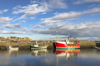 Boats moored in harbor against buildings in city