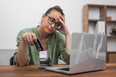 Young woman using laptop while sitting on table