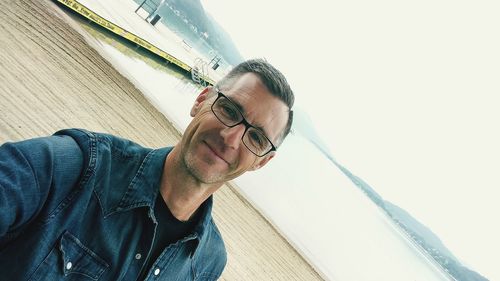 Close-up portrait of smiling mature man standing at beach