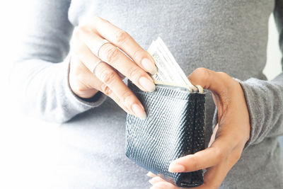 Midsection of woman removing paper currency from wallet