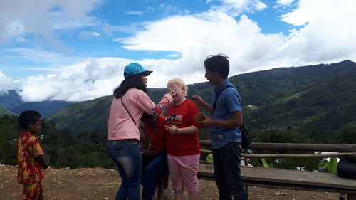 People standing on mountain against sky