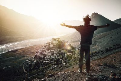 Rear view of man standing on mountain against sky
