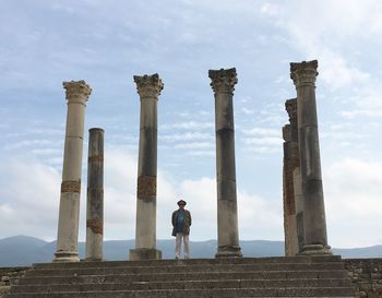 Low angle view of man standing in old ruins against sky