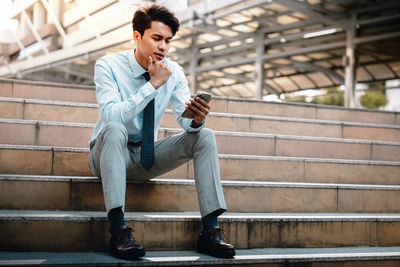 Young man looking away while sitting on staircase