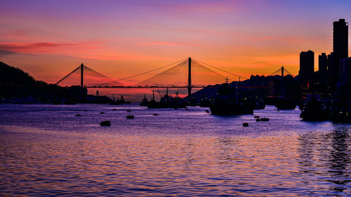 Suspension bridge over river against sky during sunset