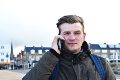 Portrait of man talking on mobile phone against sky