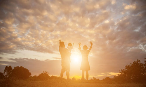 Silhouette people standing against sky during sunset