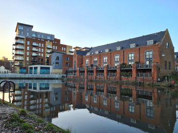 Buildings by canal against clear sky in city