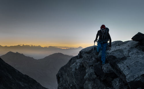 Man standing on rock with mountain range against sky