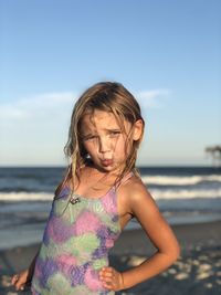 Girl standing at beach against sky