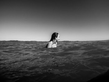 Woman enjoying in sea against clear sky