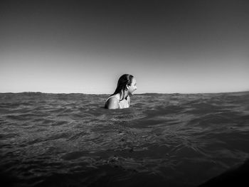 Woman standing in sea against clear sky