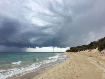 Scenic view of beach against storm clouds