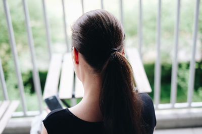 Rear view of woman sitting at table in balcony