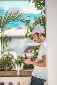 Side view of young man standing against plants