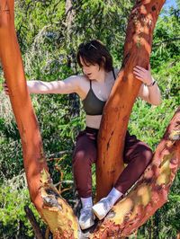 Portrait of young woman sitting in a tree.