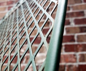 Close-up of metal fence against brick wall