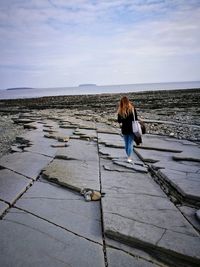 Woman walking on footpath against sky