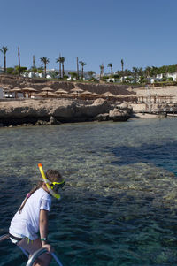 A little girl in a white t-shirt and a swimming mask dives and swims in blue sea