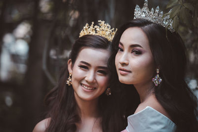 Portrait of smiling women wearing crown standing outdoors