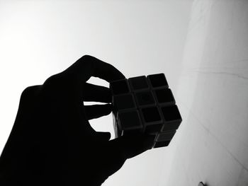 Close-up of hand holding camera against sky