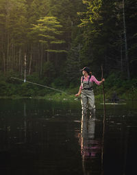 Woman standing by lake in forest