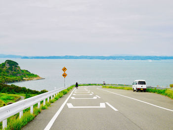 Scenic view of road by sea against sky