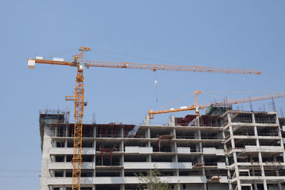 Low angle view of crane against clear blue sky