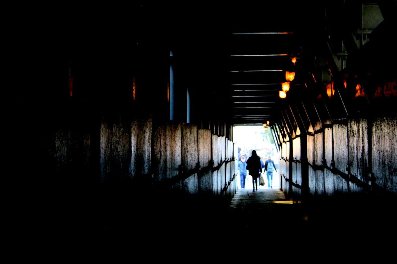 REAR VIEW OF MEN WALKING IN TUNNEL