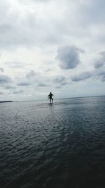 Scenic view of man surfing in the sea against cloudy sky