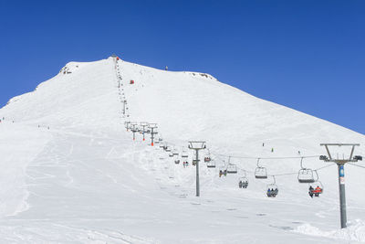 The chairlift to the top of the mountain. to the left of it and under it is a ski slope