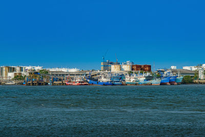 Sea by buildings against clear blue sky