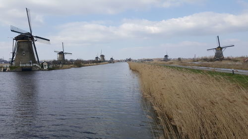 River amidst traditional windmills against sky