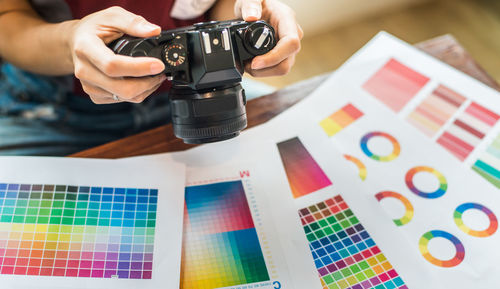 Midsection of design professional holding camera over color swatches at office