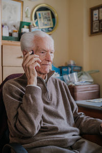 Senior man talking on mobile phone while sitting at home