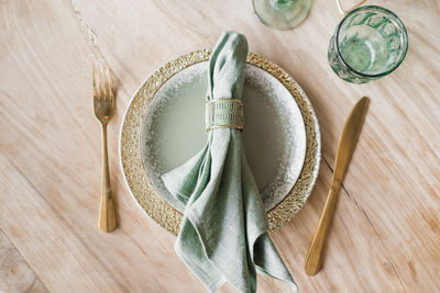 Festive table setting with plates, golden cutlery and napkin on wooden table, flat lay