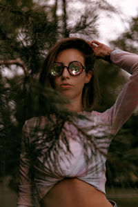 Portrait of young woman standing against trees