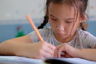 Close-up of girl writing on book