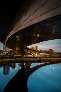 Bridge over river against sky in city at night